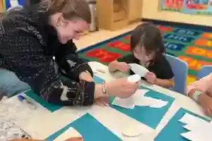 OC Kids Preschool teacher guiding a child through an art project